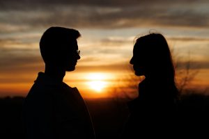 Силуэты мужчины и женщины разговаривают на закате